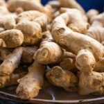 A close-up photo of fresh, raw ginger roots piled on a plate. Perfect for culinary use.