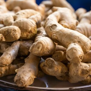 A close-up photo of fresh, raw ginger roots piled on a plate. Perfect for culinary use.