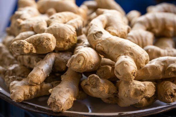 A close-up photo of fresh, raw ginger roots piled on a plate. Perfect for culinary use.