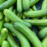Close-up of fresh organic cucumbers displayed at a local farmers market, perfect for healthy eating.