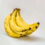 Close-up of ripe organic bananas on a neutral background, showcasing texture and freshness.