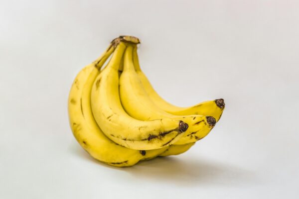 Close-up of ripe organic bananas on a neutral background, showcasing texture and freshness.