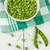 A vibrant display of green peas in a bowl with a rustic white background, ideal for food and health concepts.