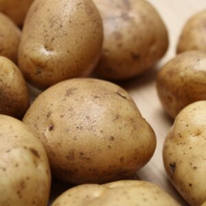 High-quality close-up photo of fresh raw potatoes on a wooden surface, ideal for food and culinary themes.